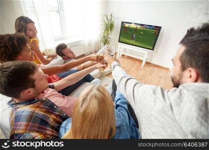 friendship, leisure and people concept - happy friends or soccer fans clinking non-alcoholic beer bottles and watching football game on tv at home. friends with beer watching football or soccer game