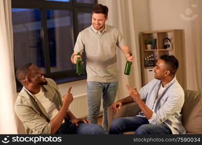 friendship, leisure and people concept - happy male friends drinking beer and talking at home at night. happy male friends drinking beer at home at night