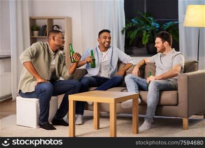 friendship, leisure and people concept - happy male friends drinking beer and talking at home at night. happy male friends drinking beer at home at night