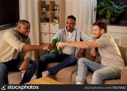 friendship, leisure and people concept - happy male friends drinking beer at home at night. happy male friends drinking beer at home at night