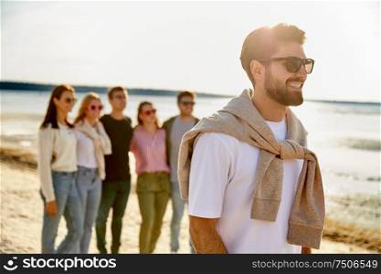 friendship, leisure and people concept - happy man with group of friends on beach in summer. happy man with friends on beach in summer