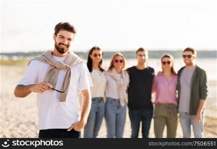 friendship, leisure and people concept - happy man with group of friends on beach in summer. happy man with friends on beach in summer