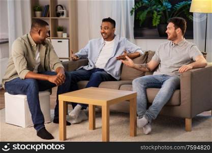 friendship, leisure and people concept - happy smiling male friends talking at home at night. happy male friends talking at home at night
