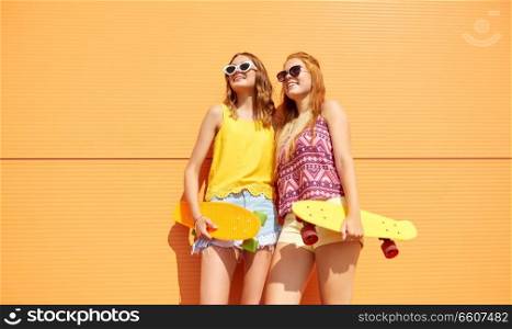 friendship, leisure and people concept - happy teenage girls or friends with short skateboards outdoors in summer. teenage girls with short skateboards outdoors