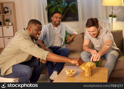 friendship, leisure and people concept - male friends drinking beer and eating crisps at home at night. male friends drinking beer with crisps at home