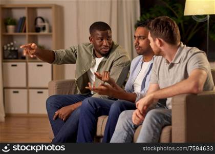 friendship, leisure and people concept - male friends watching tv and talking at home. male friends watching tv and talking at home