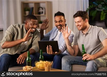 friendship, leisure and people concept - male friends with tablet pc computer having video call and drinking beer at home at night. male friends with tablet pc drinking beer at home