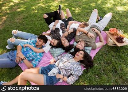 friendship, leisure and summer concept - group of happy friends chilling on picnic blanket at park. happy friends chilling on picnic blanket at summer