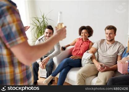 friendship, leisure, communication and entertainment concept - happy friends with popcorn and drinks talking at home