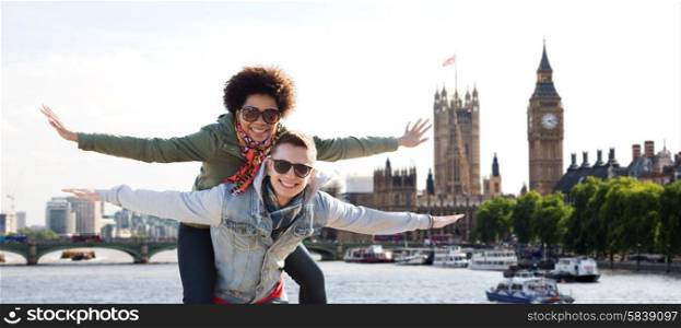 friendship, leisure, international, freedom and people concept - happy teenage couple in shades having fun over houses of parliament and thames river in london background