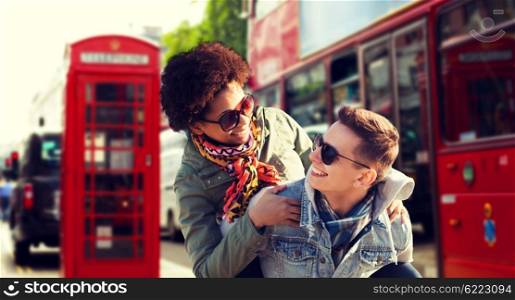 friendship, leisure, international, freedom and people concept - happy teenage couple in shades having fun over london city street background