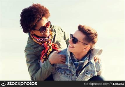 friendship, leisure, international, freedom and people concept - happy teenage couple in shades having fun outdoors