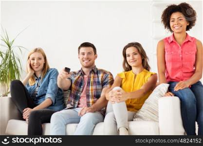 friendship, leisure, junk food, people and entertainment concept - happy friends with remote watching tv at home