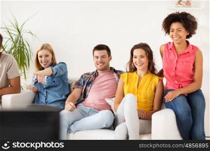 friendship, leisure, junk food, people and entertainment concept - happy friends with remote watching tv at home