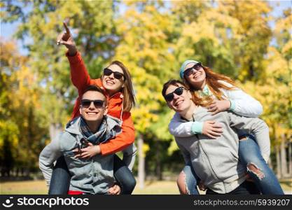 friendship, leisure, season and people concept - group of happy teenage friends in sunglasses having fun over autumn park background