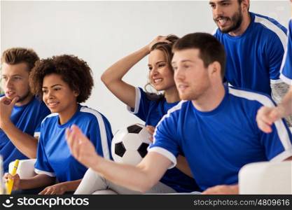 friendship, leisure, sport and entertainment concept - friends or football fans with ball watching soccer at home