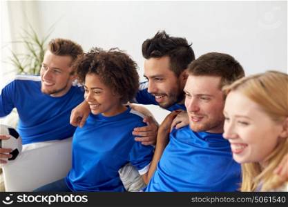 friendship, leisure, sport and entertainment concept - happy friends or football fans with ball watching soccer at home. friends or football fans watching soccer at home
