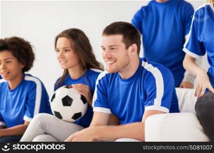 friendship, leisure, sport and entertainment concept - happy friends or football fans with ball watching soccer at home. friends or football fans watching soccer at home