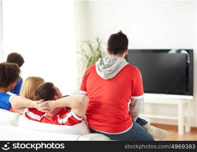 friendship, leisure, sport, people and entertainment concept - happy friends or football fans watching soccer on tv at home. friends or football fans watching tv at home