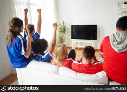 friendship, leisure, sport, people and entertainment concept - happy friends or football fans watching soccer on tv and celebrating victory at home. friends or football fans watching tv at home