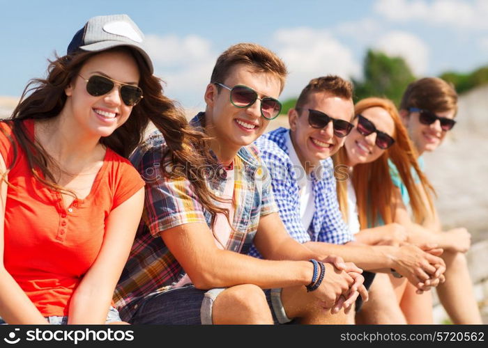 friendship, leisure, summer and people concept - close up of smiling friends sitting on city street