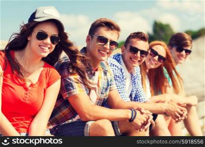 friendship, leisure, summer and people concept - close up of smiling friends sitting on city street