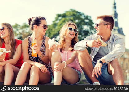 friendship, leisure, summer and people concept - group of smiling friends in sunglasses sitting with food on city square