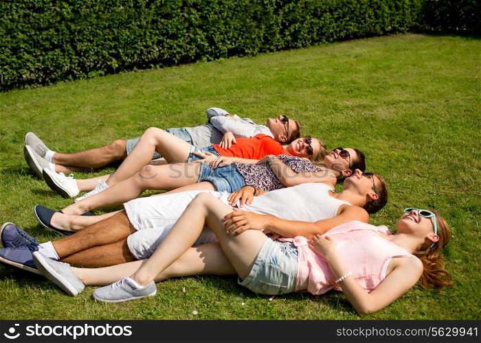 friendship, leisure, summer and people concept - group of smiling friends lying on grass outdoors