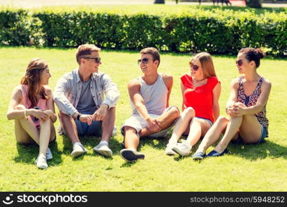 friendship, leisure, summer and people concept - group of smiling friends outdoors sitting on grass in park