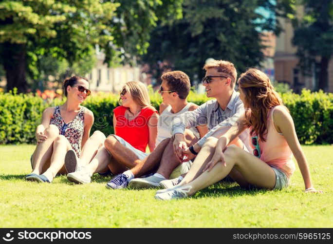 friendship, leisure, summer and people concept - group of smiling friends outdoors sitting on grass in park