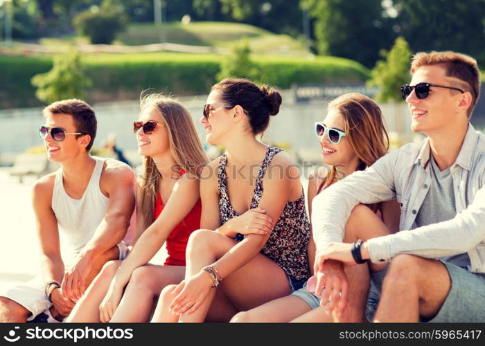 friendship, leisure, summer and people concept - group of smiling friends sitting on city square