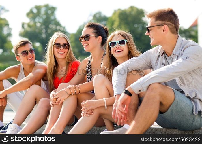 friendship, leisure, summer and people concept - group of smiling friends sitting on city street