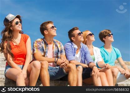 friendship, leisure, summer and people concept - group of smiling friends sitting on city street