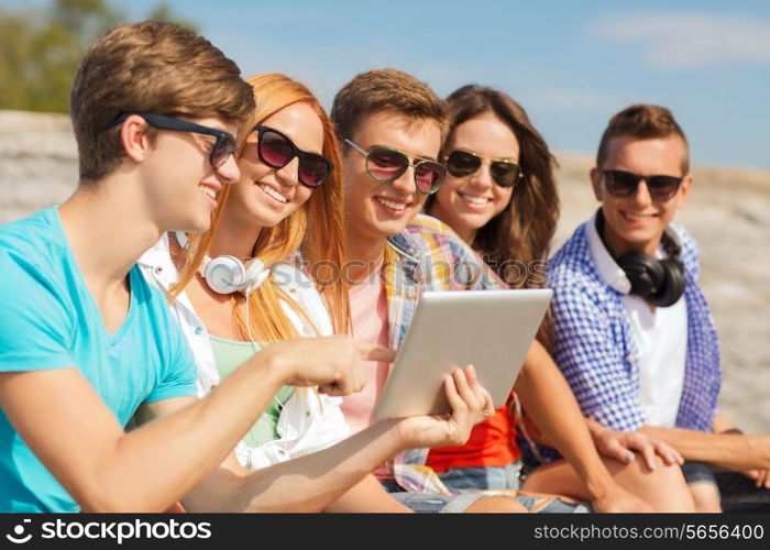 friendship, leisure, summer and people concept - group of smiling friends with tablet pc computer sitting outdoors