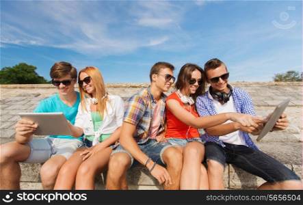 friendship, leisure, summer and people concept - group of smiling friends with tablet pc computers sitting outdoors