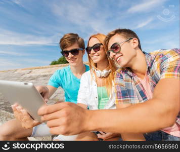 friendship, leisure, summer and people concept - group of smiling friends with tablet pc computers sitting outdoors