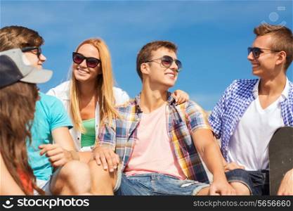 friendship, leisure, summer and people concept - group of smiling friends with skateboard sitting on city street