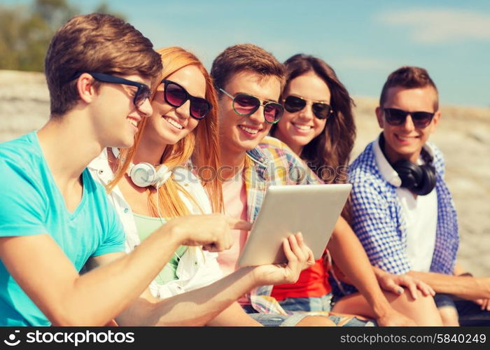 friendship, leisure, summer and people concept - group of smiling friends with tablet pc computer sitting outdoors