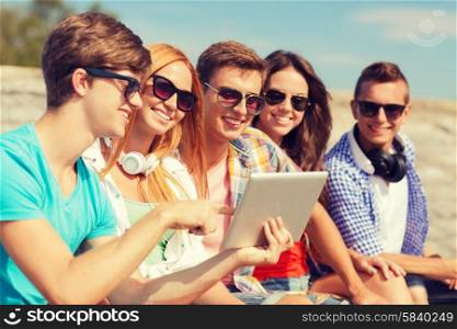 friendship, leisure, summer and people concept - group of smiling friends with tablet pc computer sitting outdoors