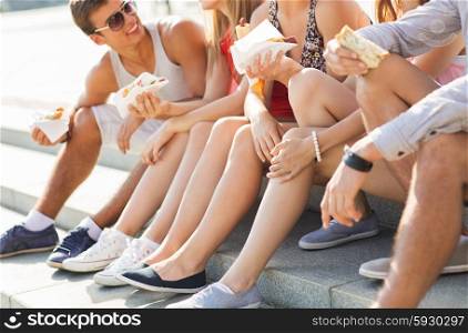 friendship, leisure, summer, fast food and people concept - group of happy friends eating hot dogs and sandwiches on city square