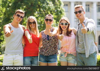 friendship, leisure, summer, gesture and people concept - group of smiling friends showing thumbs up outdoors