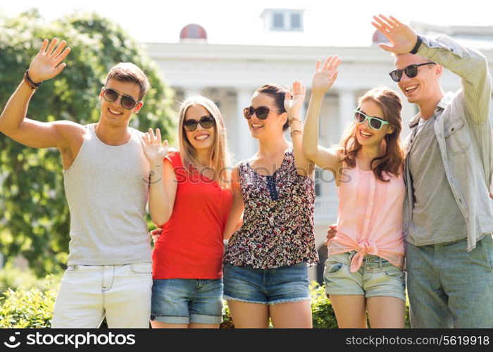 friendship, leisure, summer, gesture and people concept - group of smiling friends waving hands outdoors