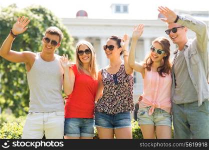 friendship, leisure, summer, gesture and people concept - group of smiling friends waving hands outdoors
