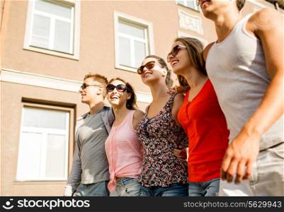 friendship, leisure, summer, gesturer and people concept - group of smiling friends walking in city