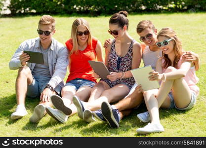 friendship, leisure, summer, technology and people concept - group of smiling friends with tablet pc computers sitting on grass in park