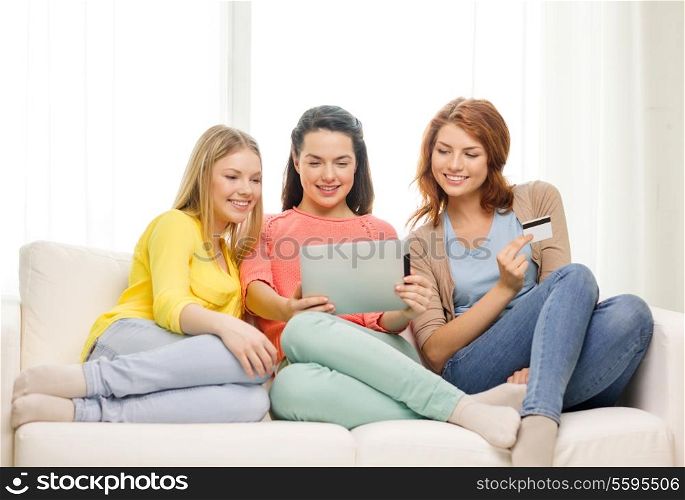 friendship, money, technology and internet concept - three smiling teenage girls with tablet pc computer and credit card at home