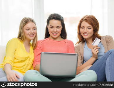 friendship, money, technology and internet concept - three smiling teenage girls with laptop computer and credit card at home