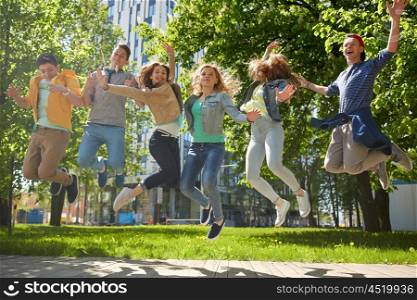 friendship, motion, action, freedom and people concept - group of happy teenage students or friends jumping outdoors