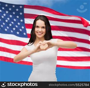 friendship, patriotic and happy people concept - smiling girl in white t-shirt showing heart with hands