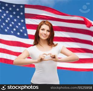 friendship, patriotic and happy people concept - smiling girl in white t-shirt showing heart with hands
